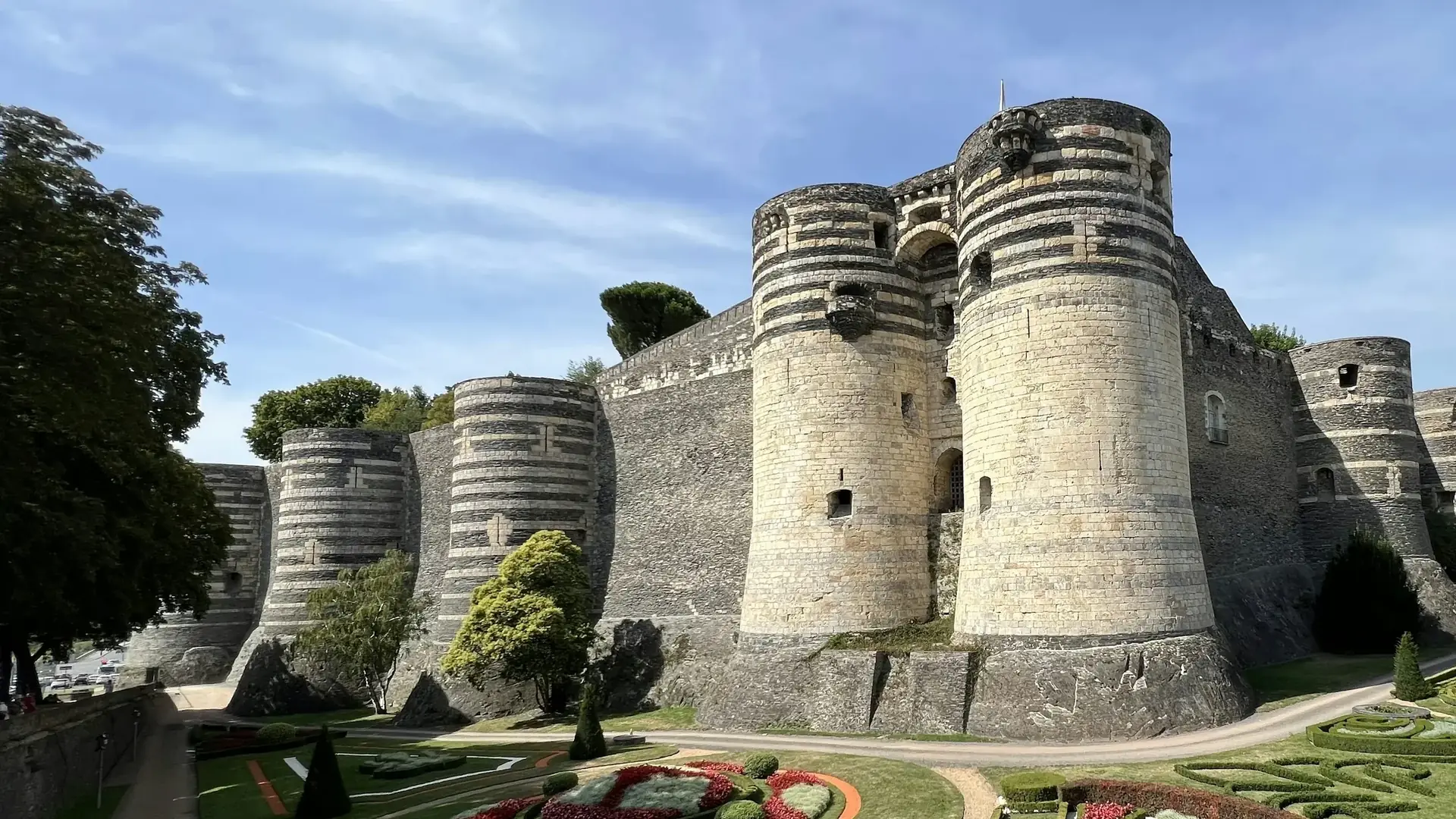 The striped drum towers of the Château d'Angers rising above its moat-garden parterre